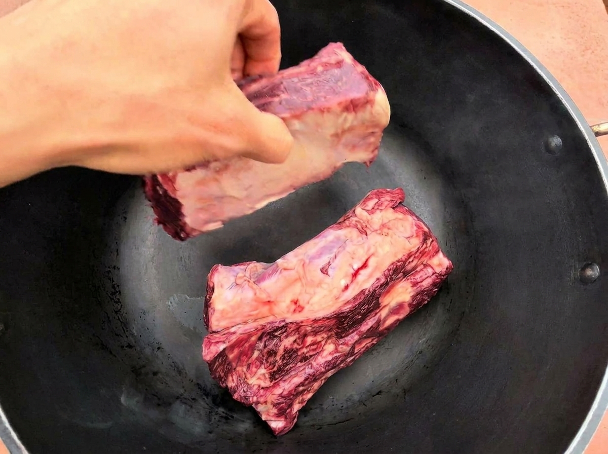 달궈진 팬에 커다란 생소갈비 두 대를 올리는 모습
