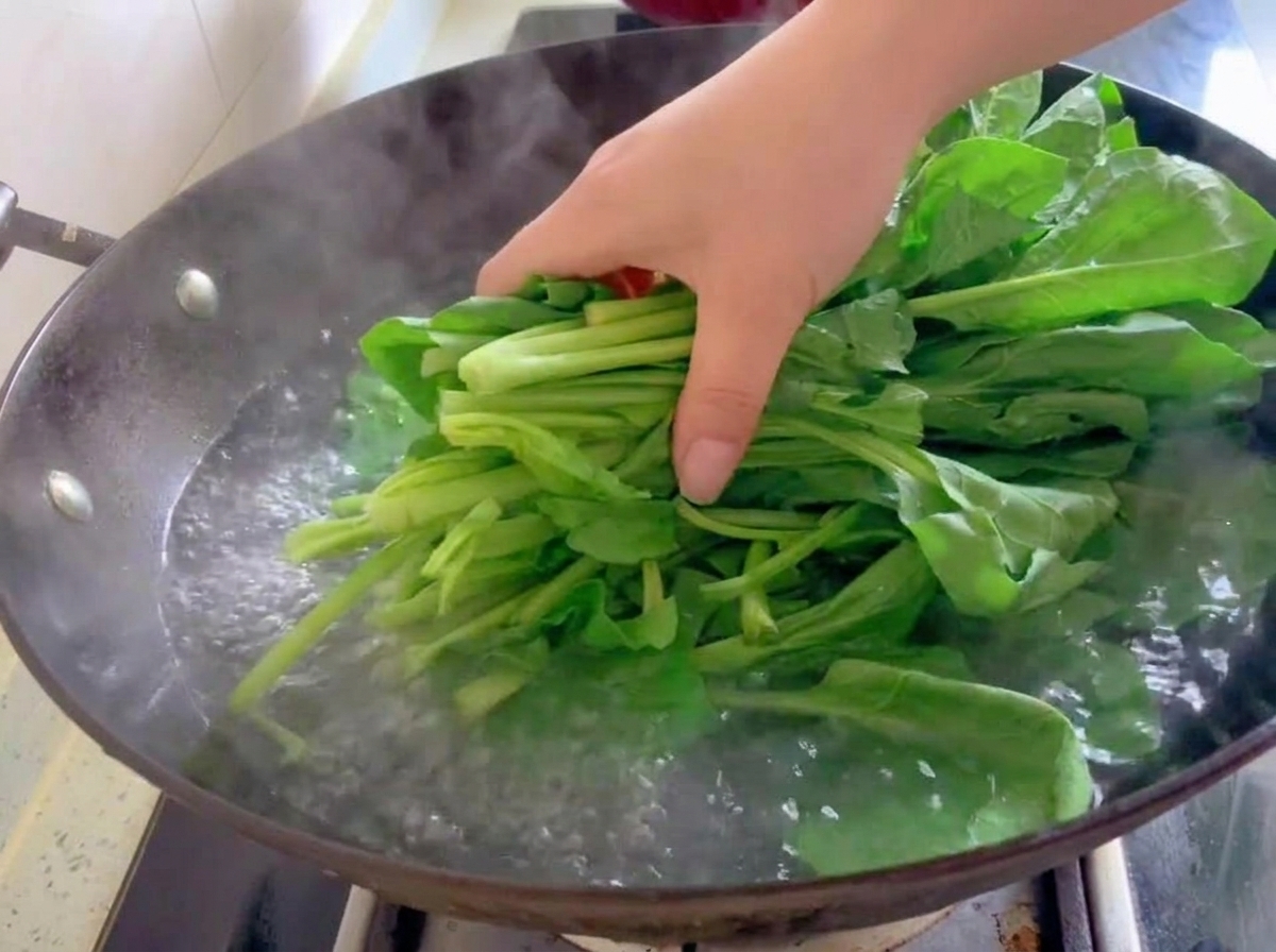 숙주를 데치던 웍의 끓는 물에 신선한 시금치를 넣는 모습.