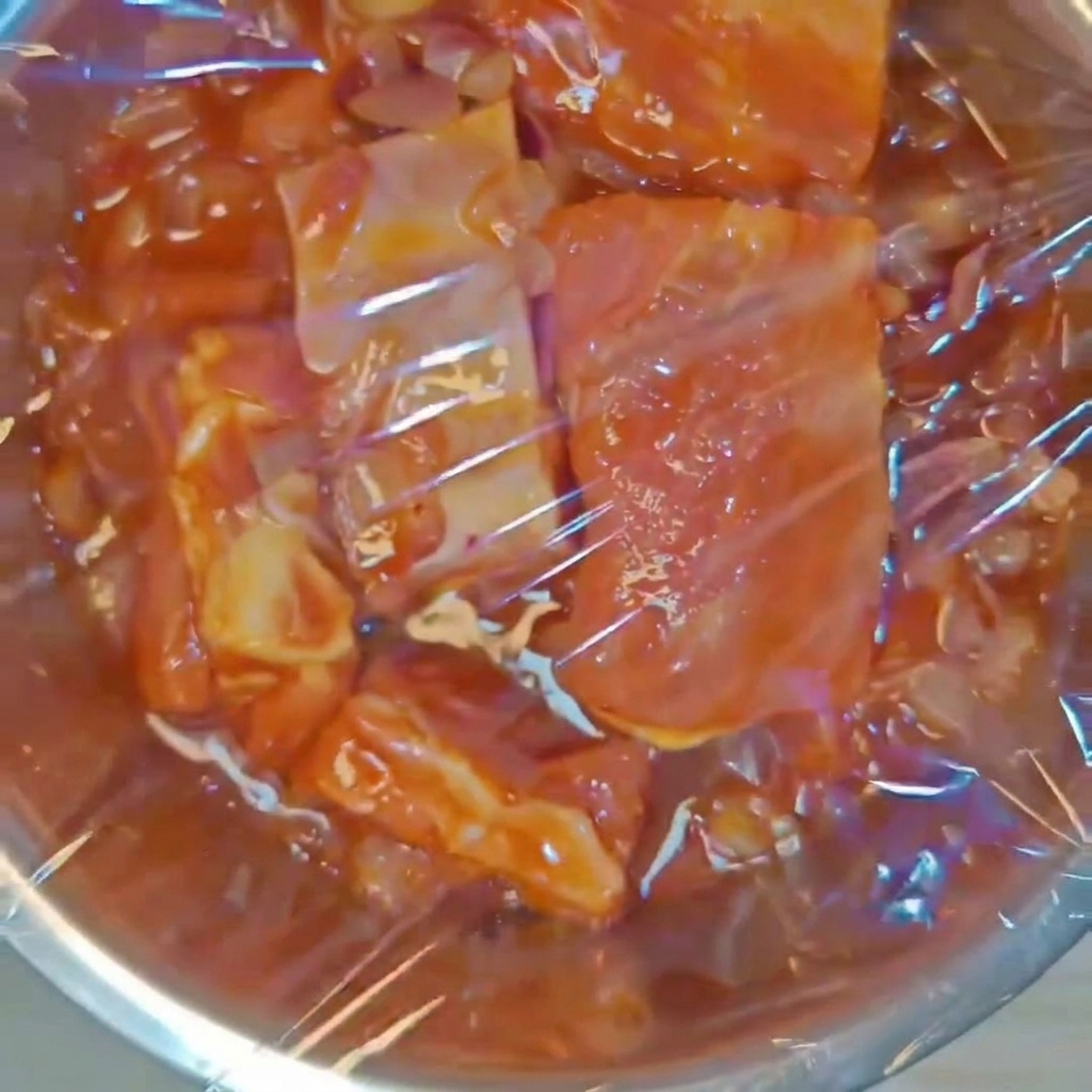 양념된 폭립이 담긴 스테인리스 볼을 투명한 위생랩으로 단단하게 밀봉한 모습