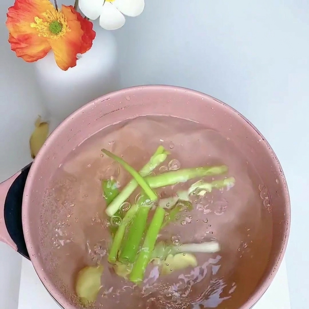 대파, 생강, 팔각을 넣은 물에 닭다리를 넣고 삶는 모습.