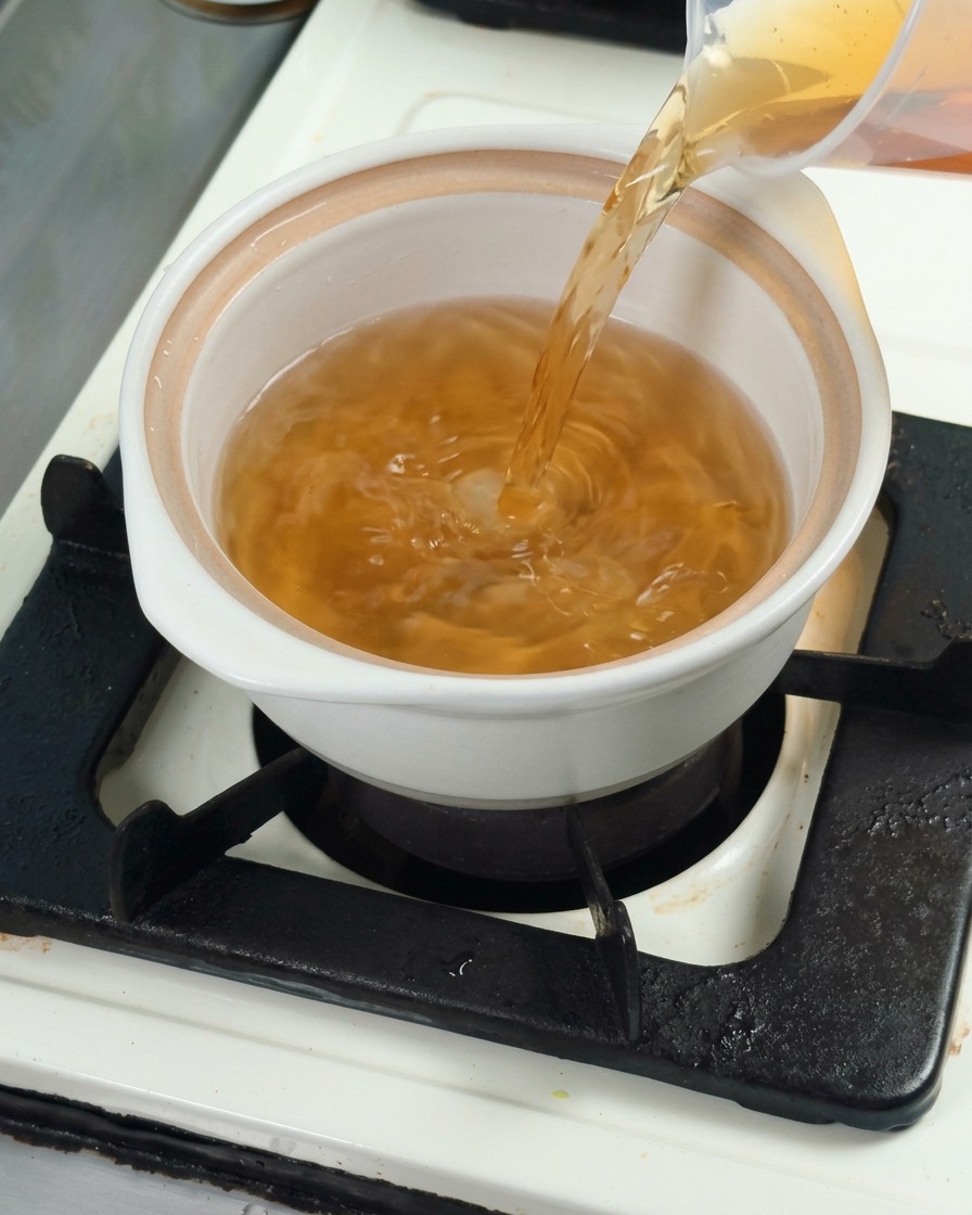 흰 냄비에 다시마 육수를 붓고 요리 베이스를 준비하는 모습.