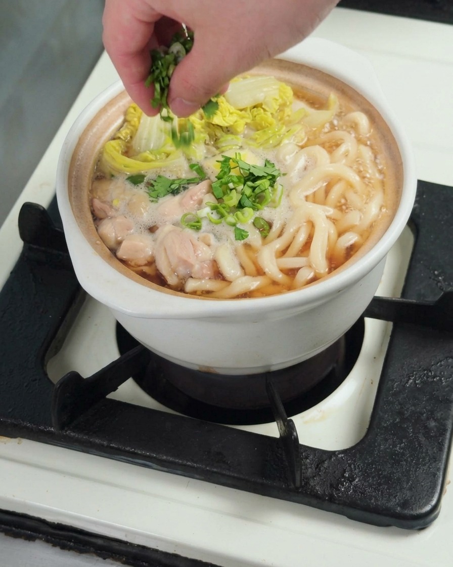 완성된 치킨 우동 그릇 위에 송송 썬 대파를 뿌리는 모습.