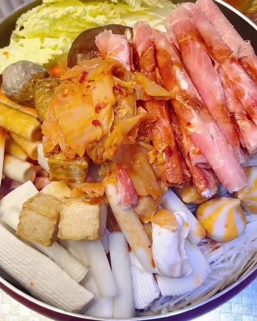 재료 위에 다진 김치를 올리고 물을 붓는 모습.