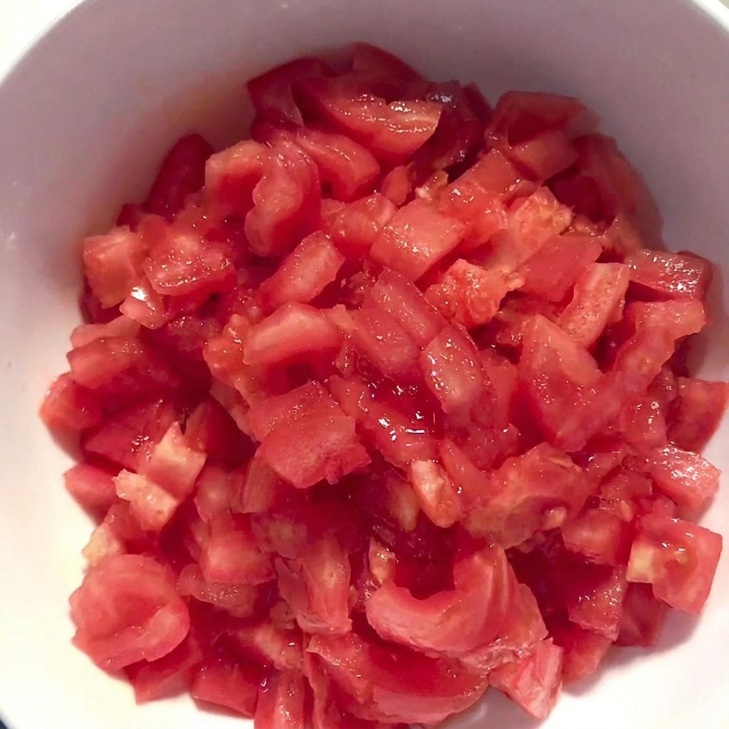 껍질을 벗겨 잘게 썬 토마토가 담긴 흰색 볼.