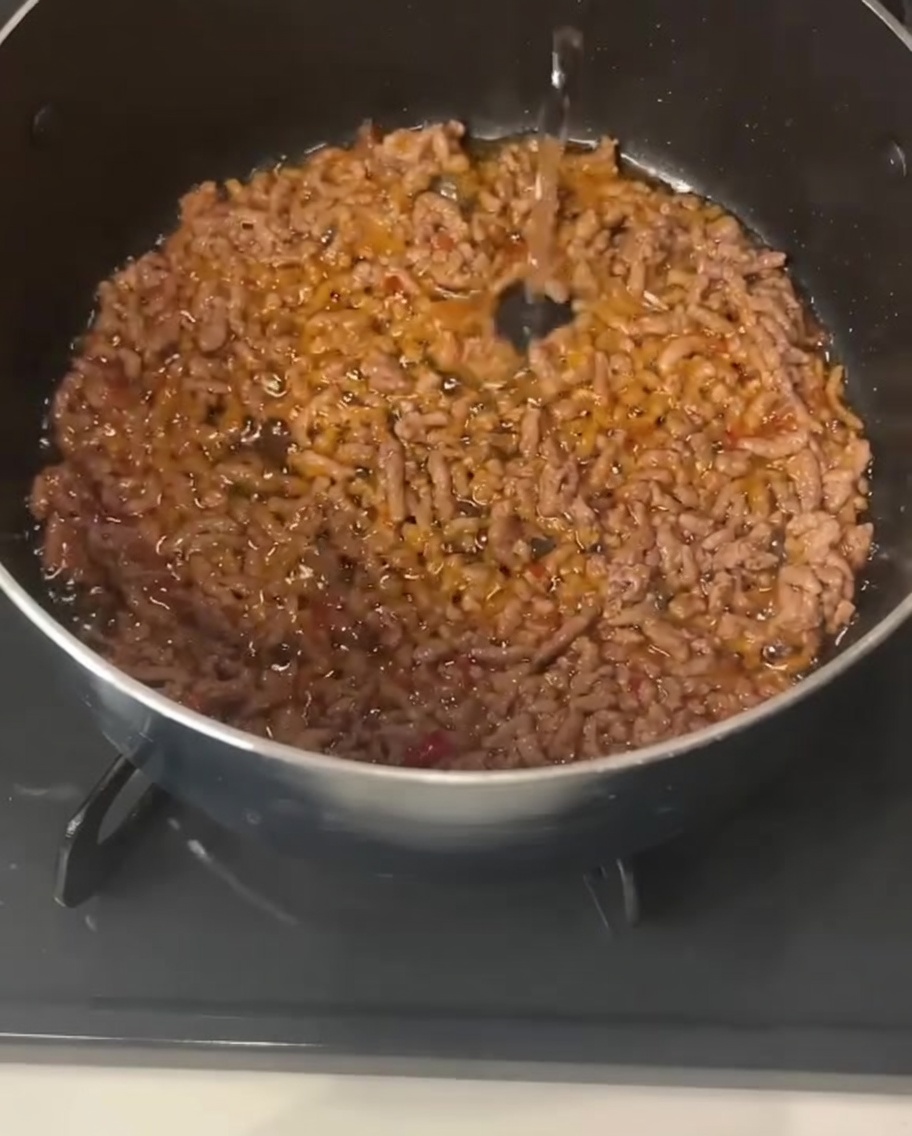 익힌 돼지고기가 담긴 냄비에 투명한 액체를 붓는 모습.