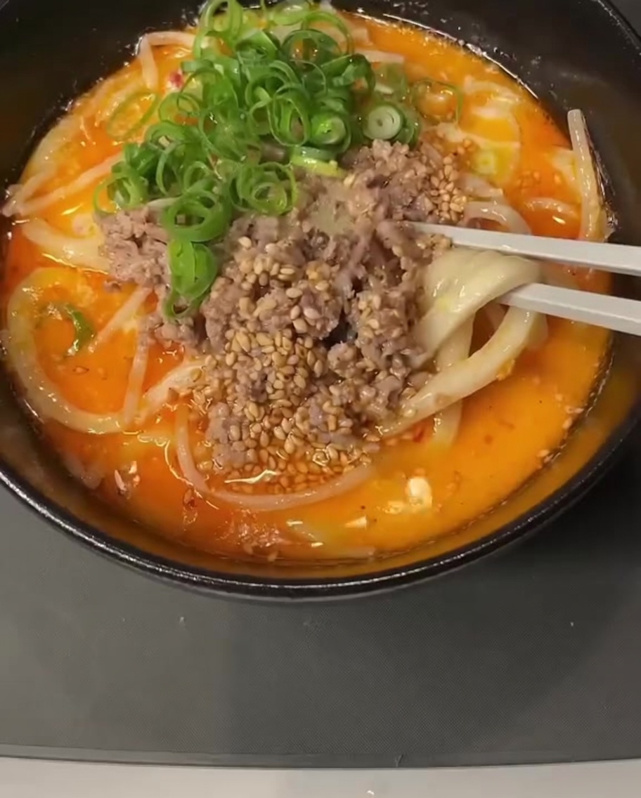 크리미한 액체 혼합물이 담긴 냄비에 된장 한 숟가락을 넣고 푸는 모습.