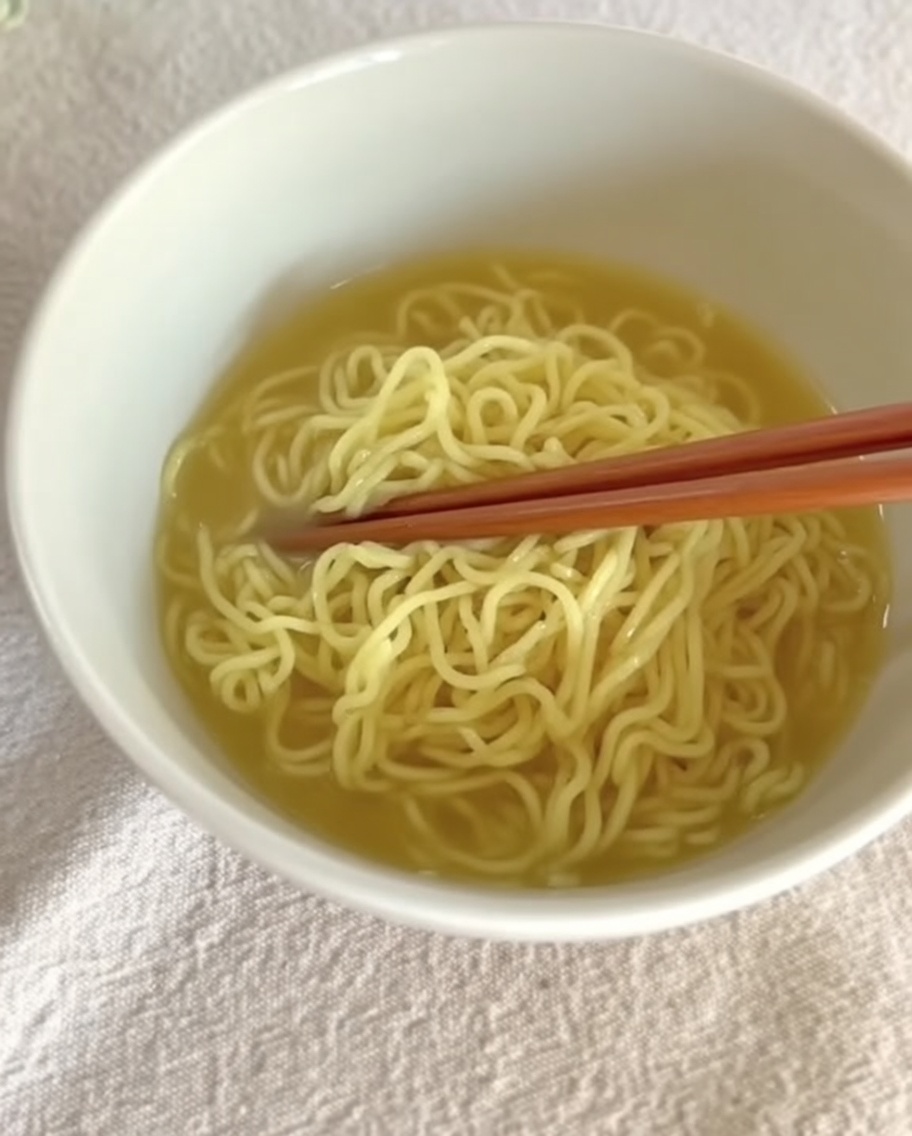 그릇에 담긴 면 위로 크리미한 탄탄멘 국물을 붓는 모습.