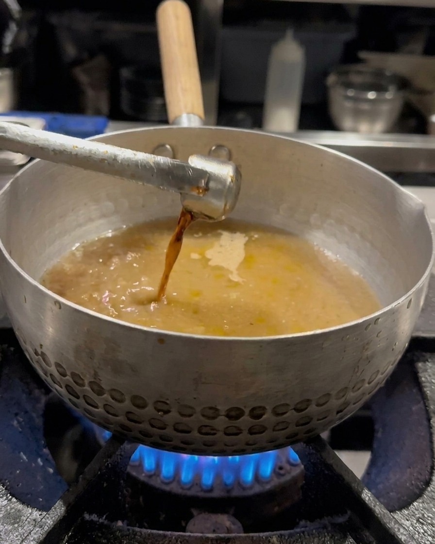 육수가 담긴 냄비에 간장을 넣고 거품기로 젓는 모습.