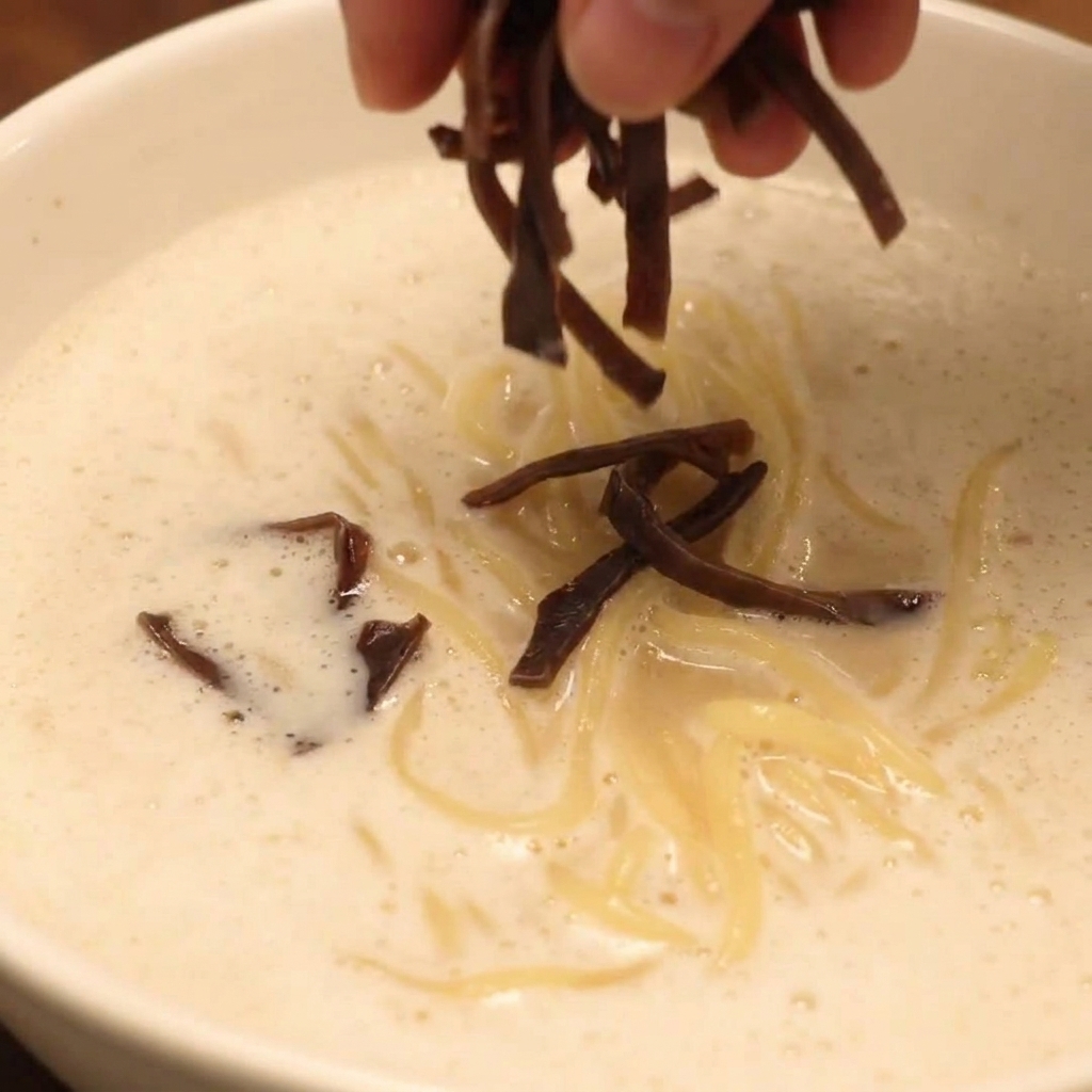 차슈, 버섯, 신선한 야채가 올라간 완성된 치킨 파이탄 폼 라멘 그릇.