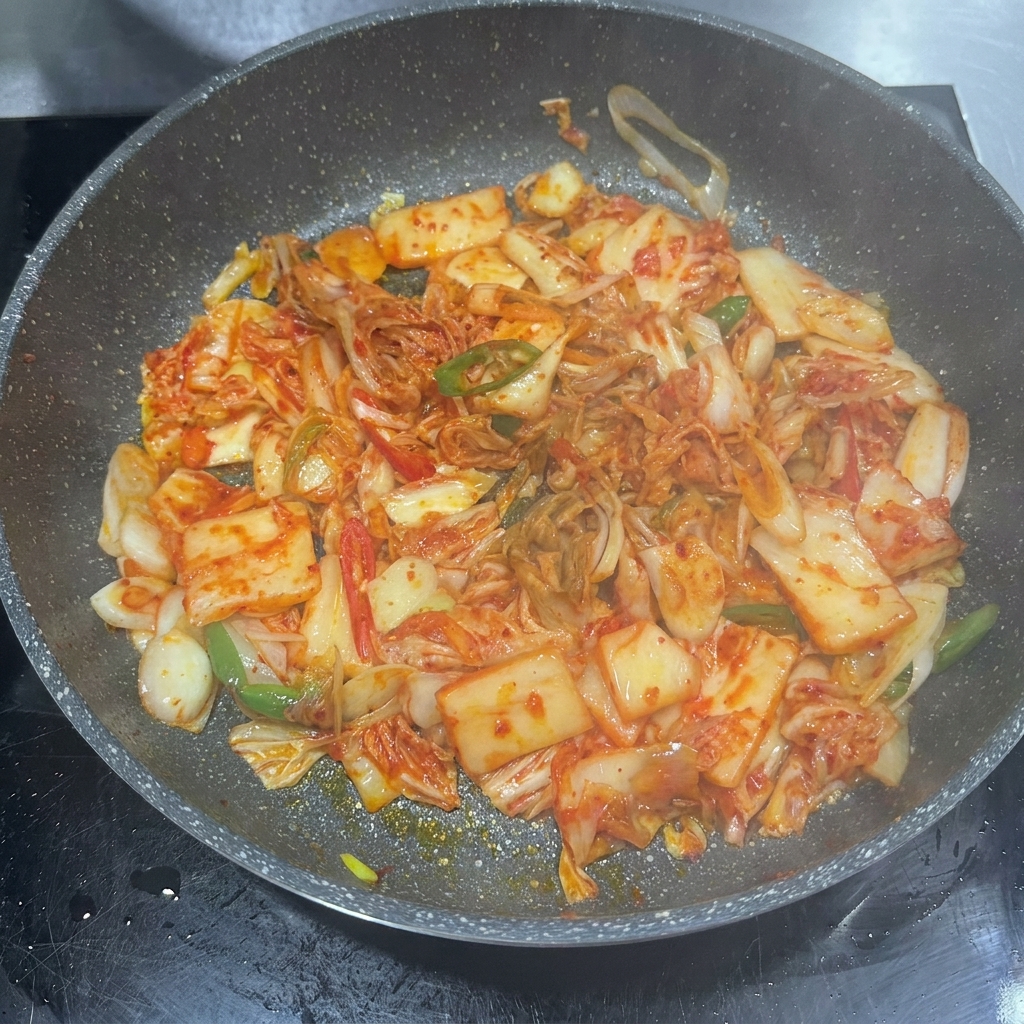 볶은 김치에 고추장, 간장, 설탕을 넣고 함께 섞는 모습.
