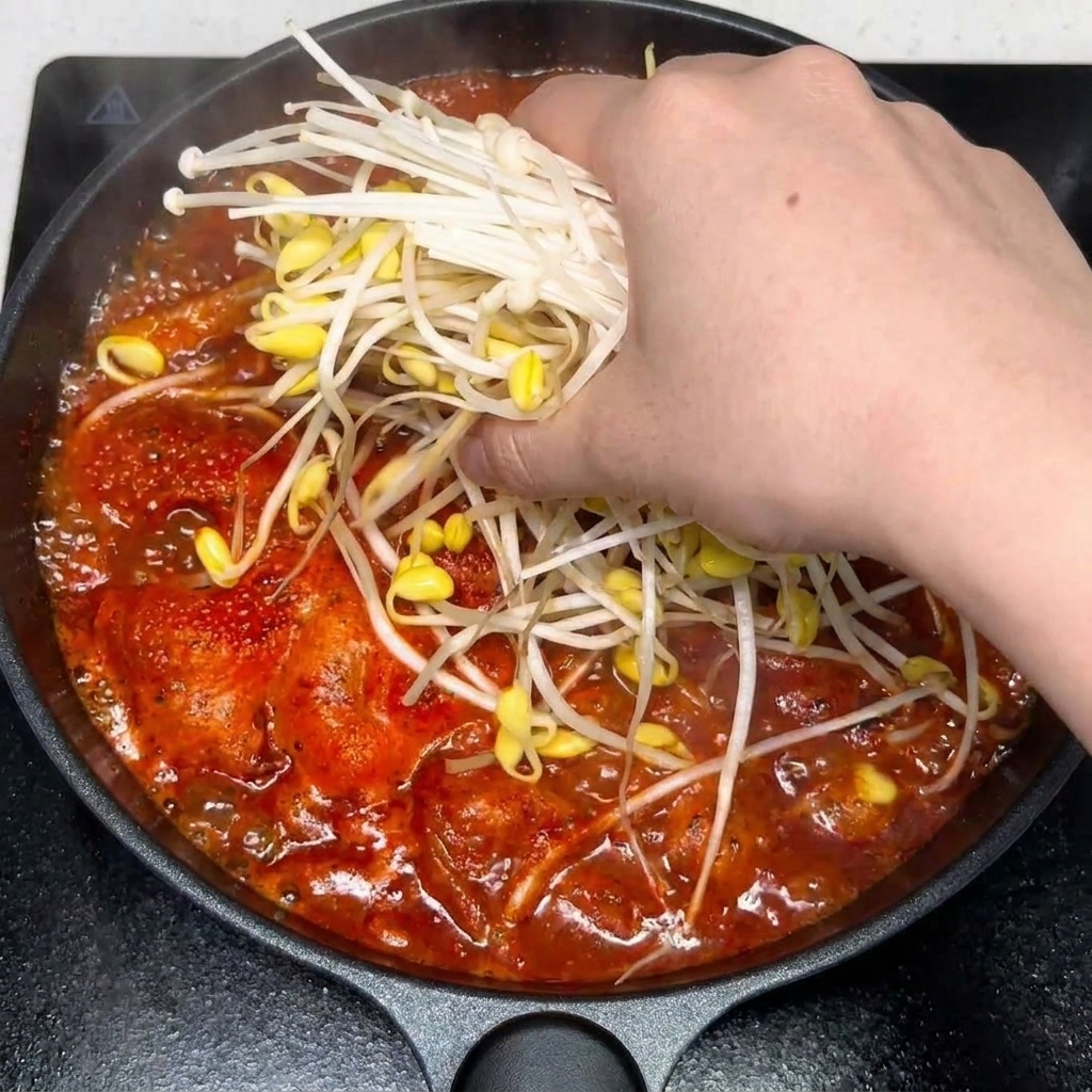 얼큰한 김치찌개에 다진 마늘과 양념을 넣는 모습.