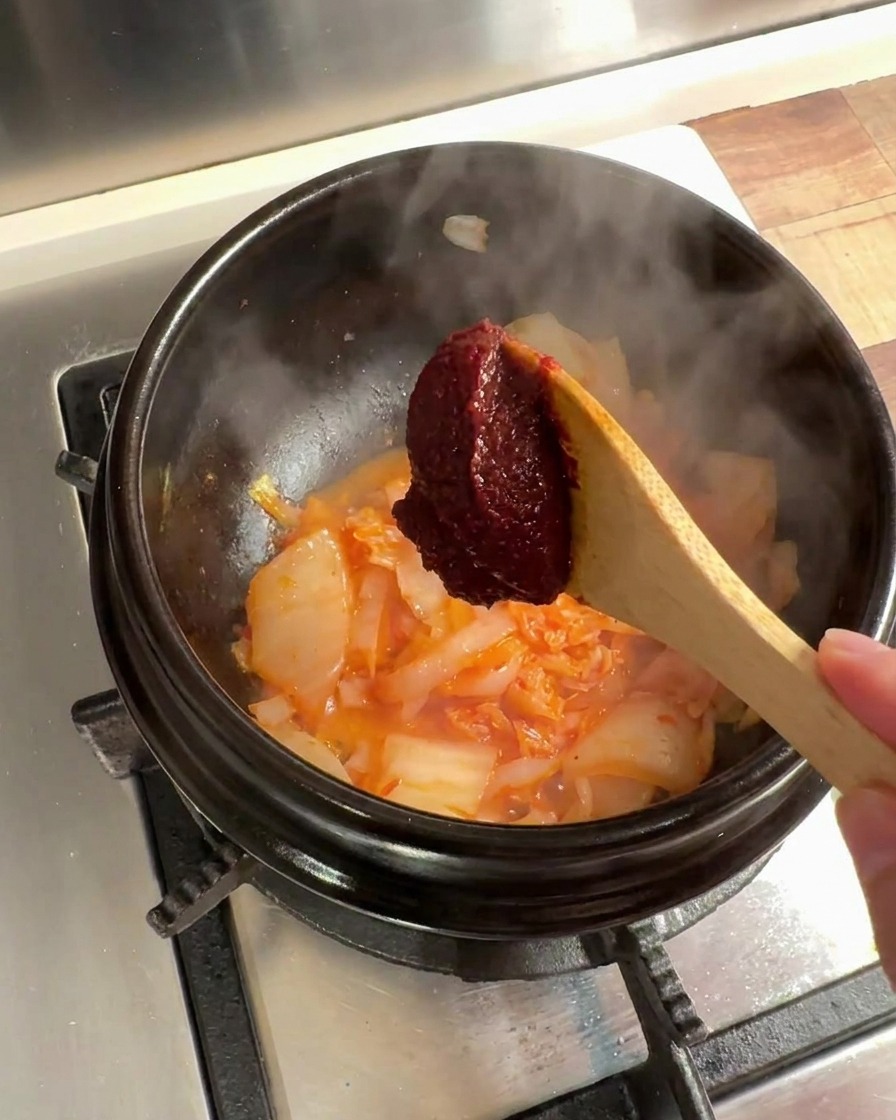 김치와 양파 볶은 것에 고추장을 추가하는 모습.