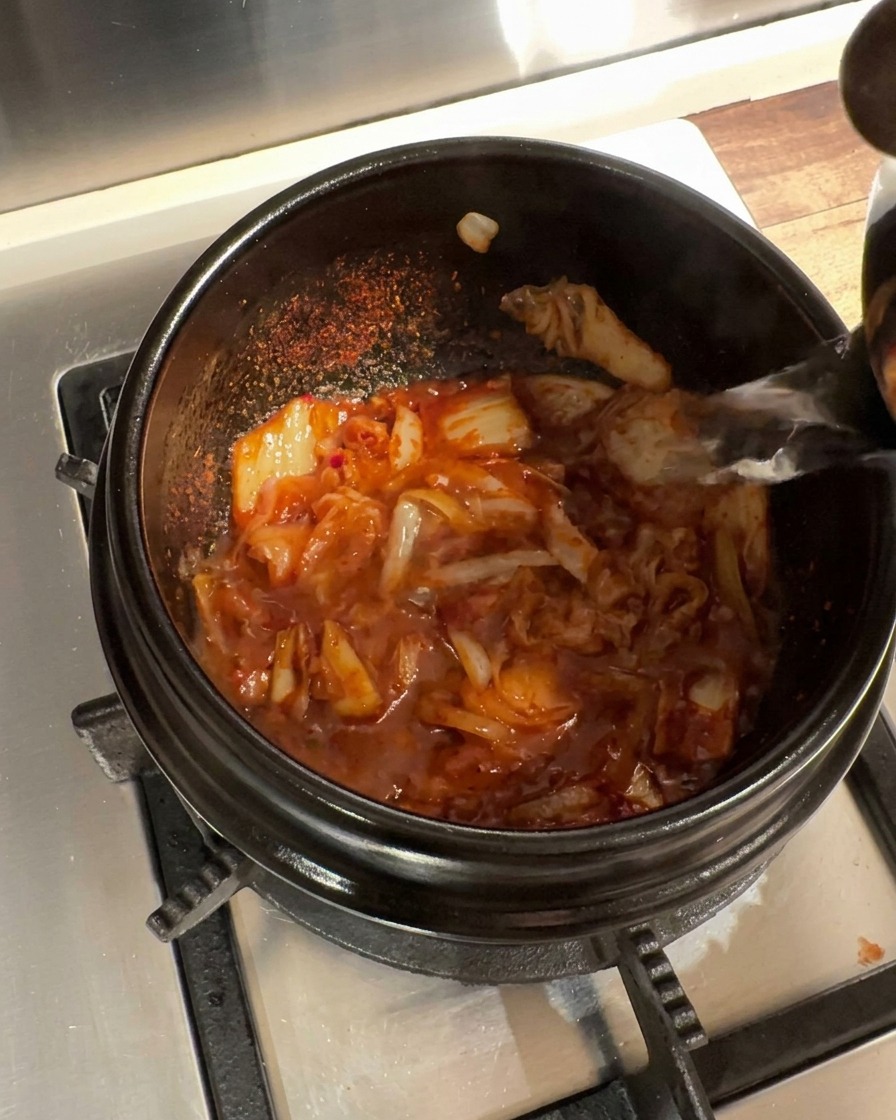 양념한 김치 베이스에 끓는 물을 붓는 모습.