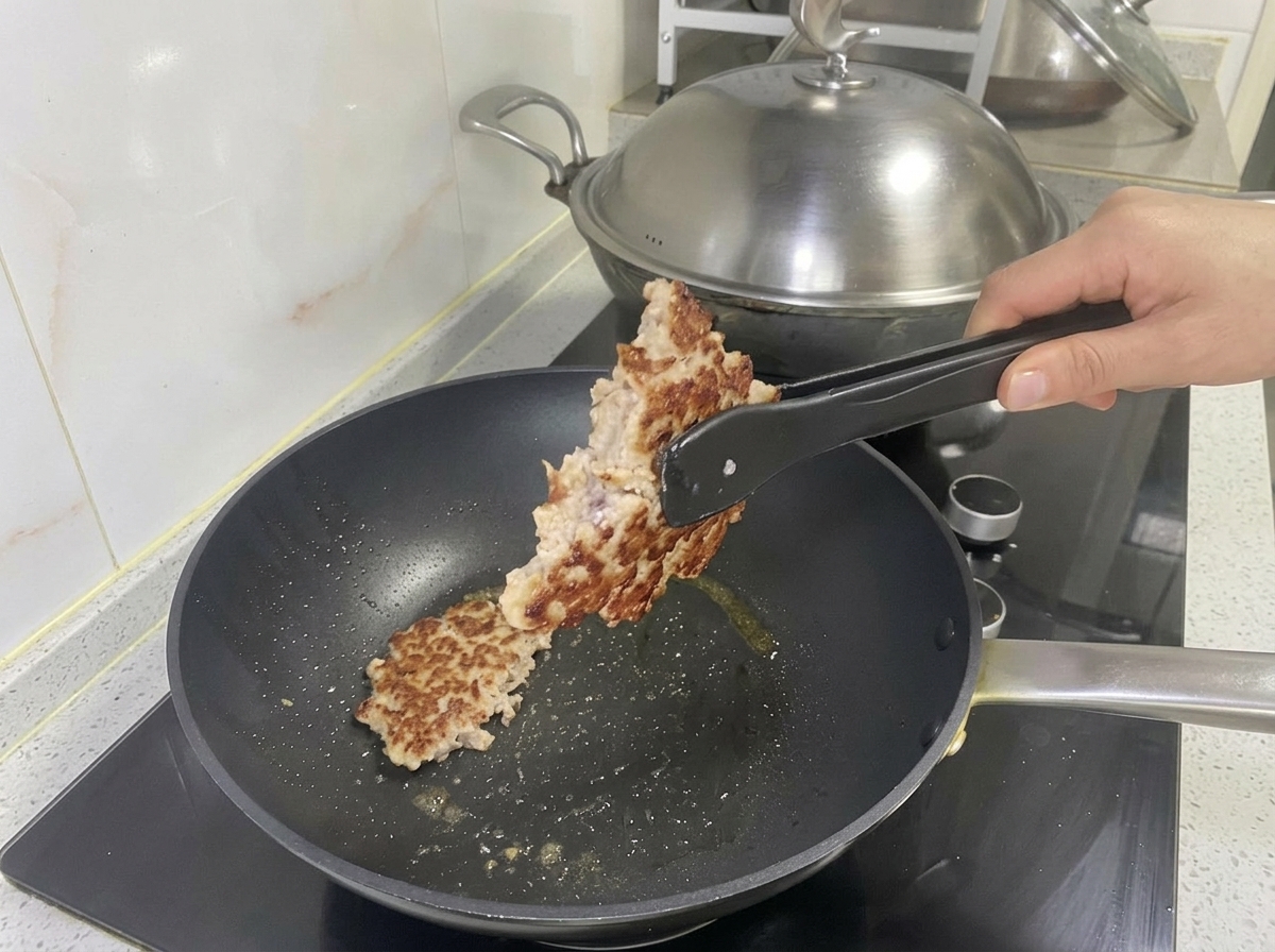 잘 구워진 돼지고기 패티를 집게로 들어 올리는 모습.