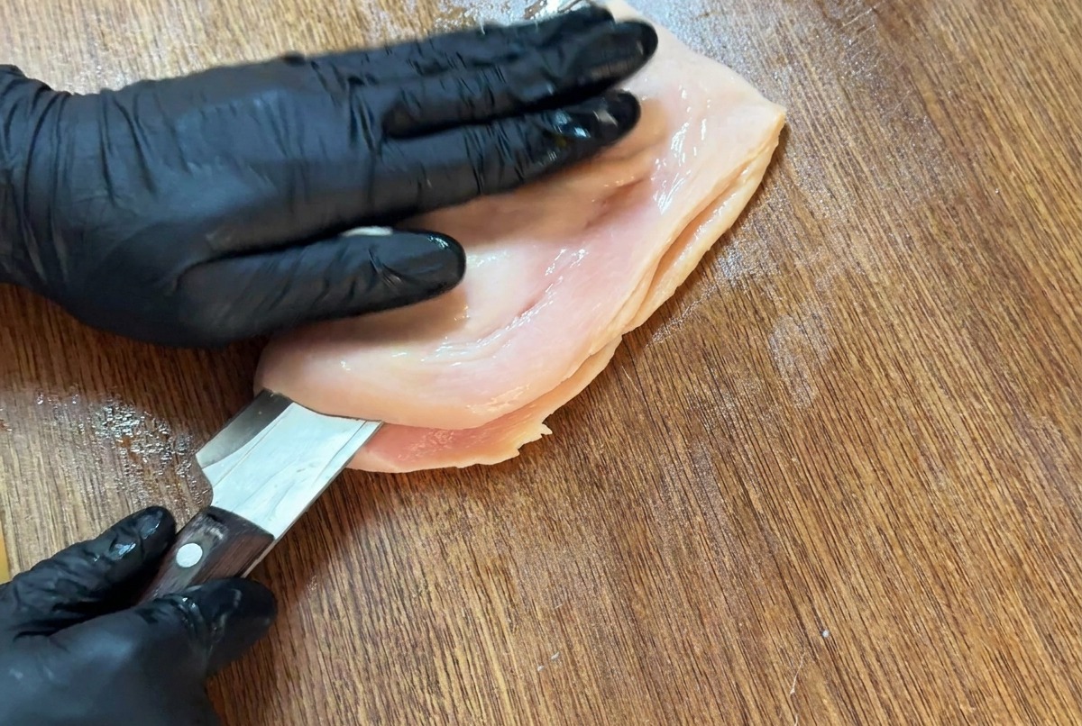 칼을 수평으로 넣어 닭가슴살을 나비 모양으로 펼치는 모습.