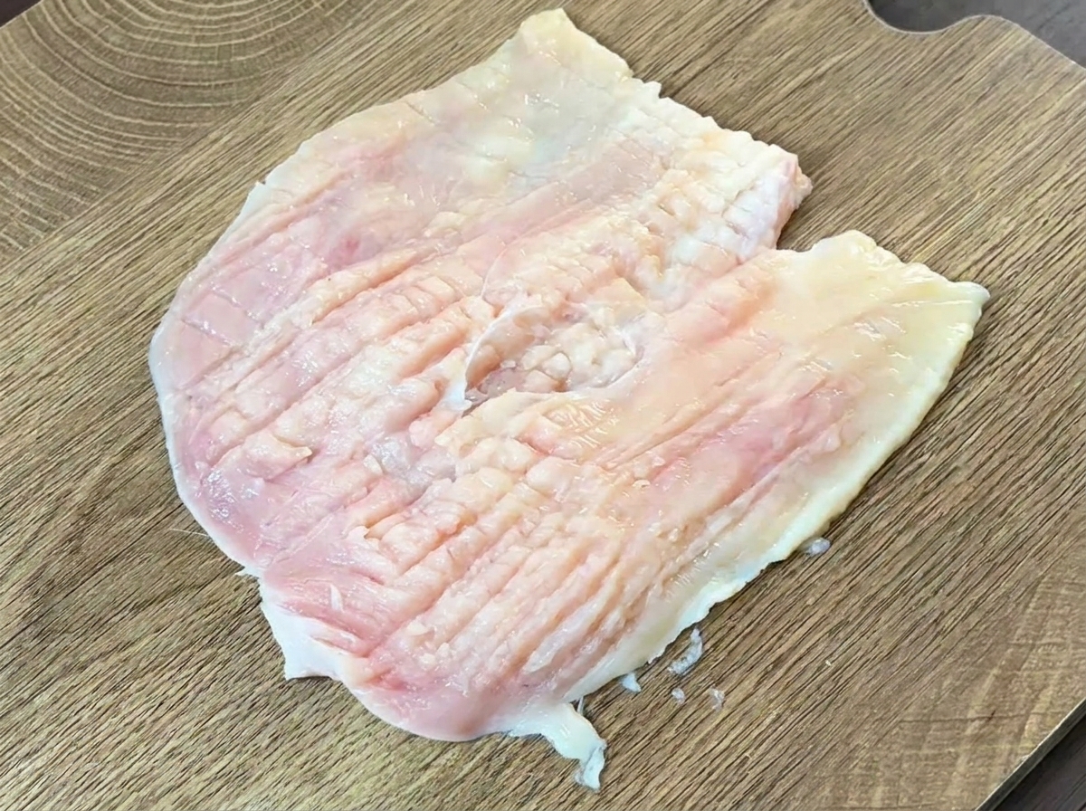 칼등으로 펼친 닭가슴살을 두드리는 모습.