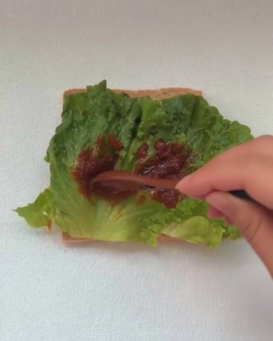 상추 층 위에 잘 익은 계란 프라이를 올리는 모습.