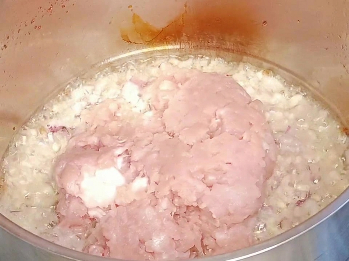 볶은 양파와 마늘 위에 다진 고기를 넣는 모습.
