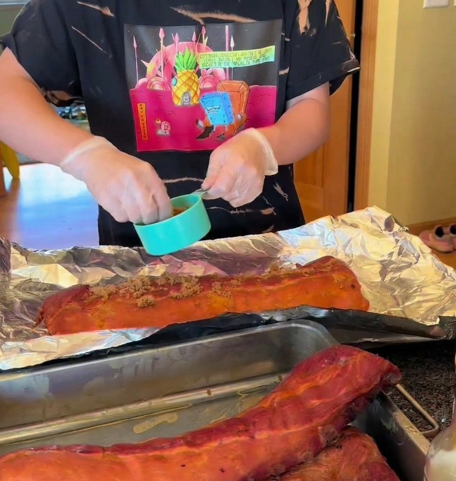 알루미늄 호일 위에서 훈연된 갈비에 건조 시즈닝을 뿌리고 꿀을 뿌리는 모습.