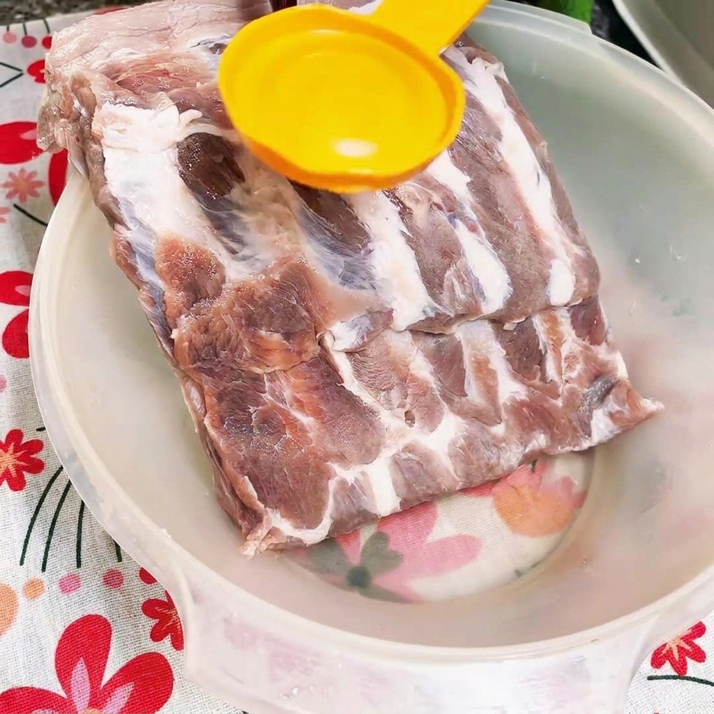 흰색 볼에 담긴 생돼지갈비 위에 굴소스를 붓는 모습.