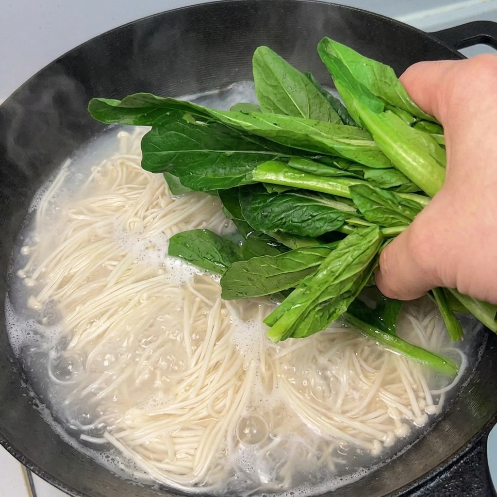 끓는 국수에 녹색 채소를 넣는 모습.