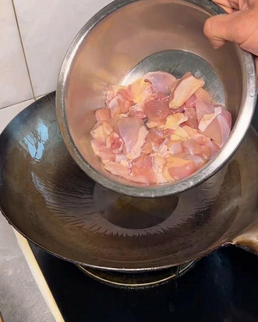 뜨거운 웍에 생닭다리살 조각을 넣는 모습.