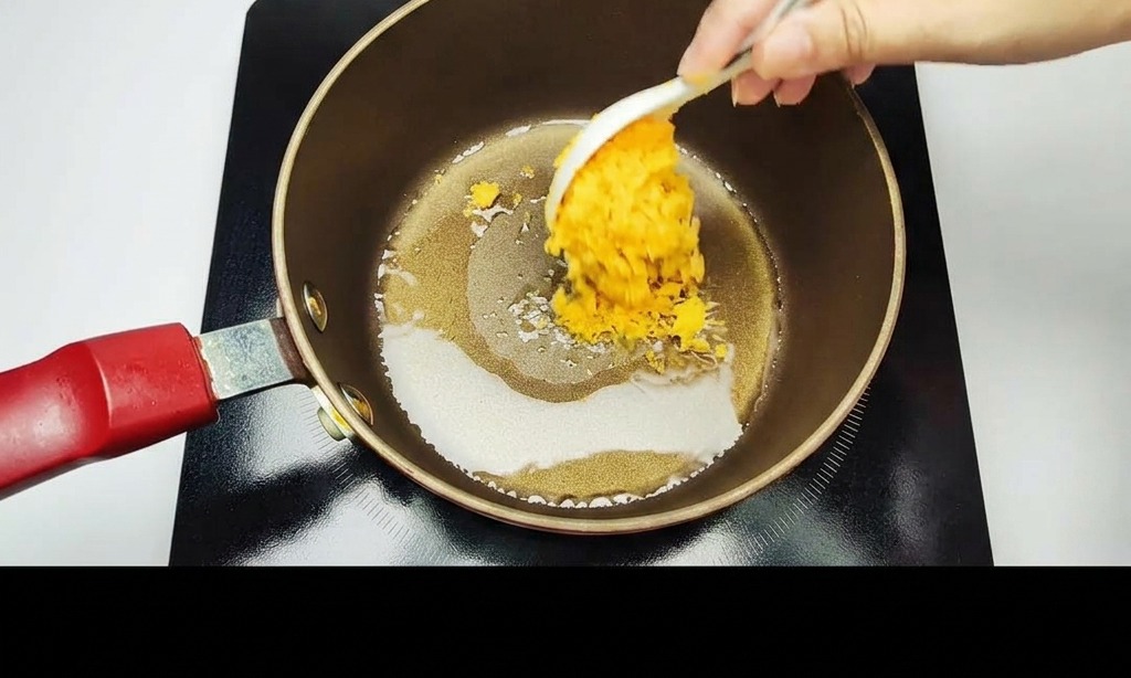 논스틱 냄비에 으깬 황금빛 염장 노른자를 흰 숟가락으로 저으며 볶는 모습