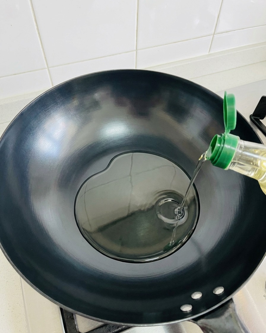 뜨겁게 달궈진 빈 웍에 올리브 오일을 두르는 모습.