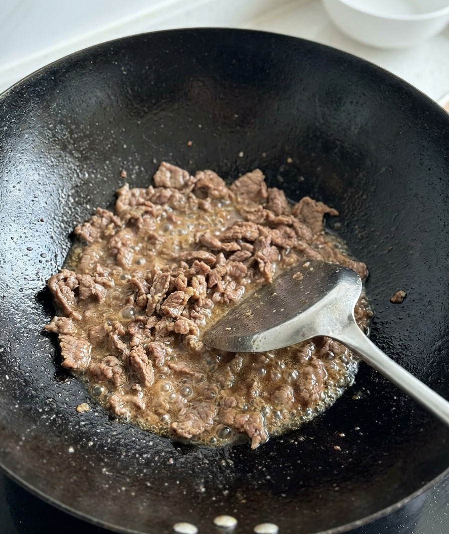 볶은 소고기가 있는 웍에 깍둑썰기한 생 토마토를 넣는 모습.