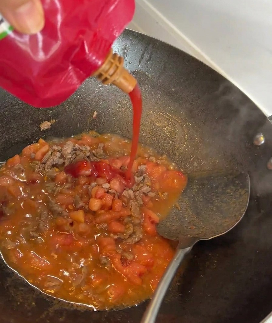 소고기와 토마토가 볶아지는 팬에 토마토 페이스트를 넣는 모습.
