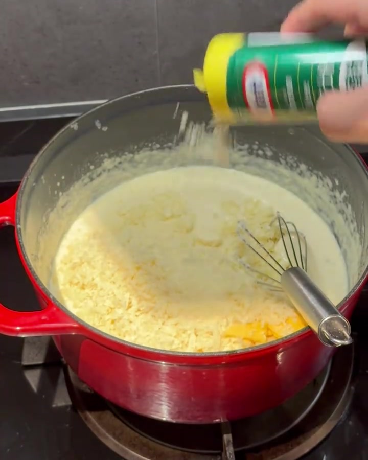 빨간 냄비의 크리미한 소스에 치즈 파우더를 넣고 젓는 모습.