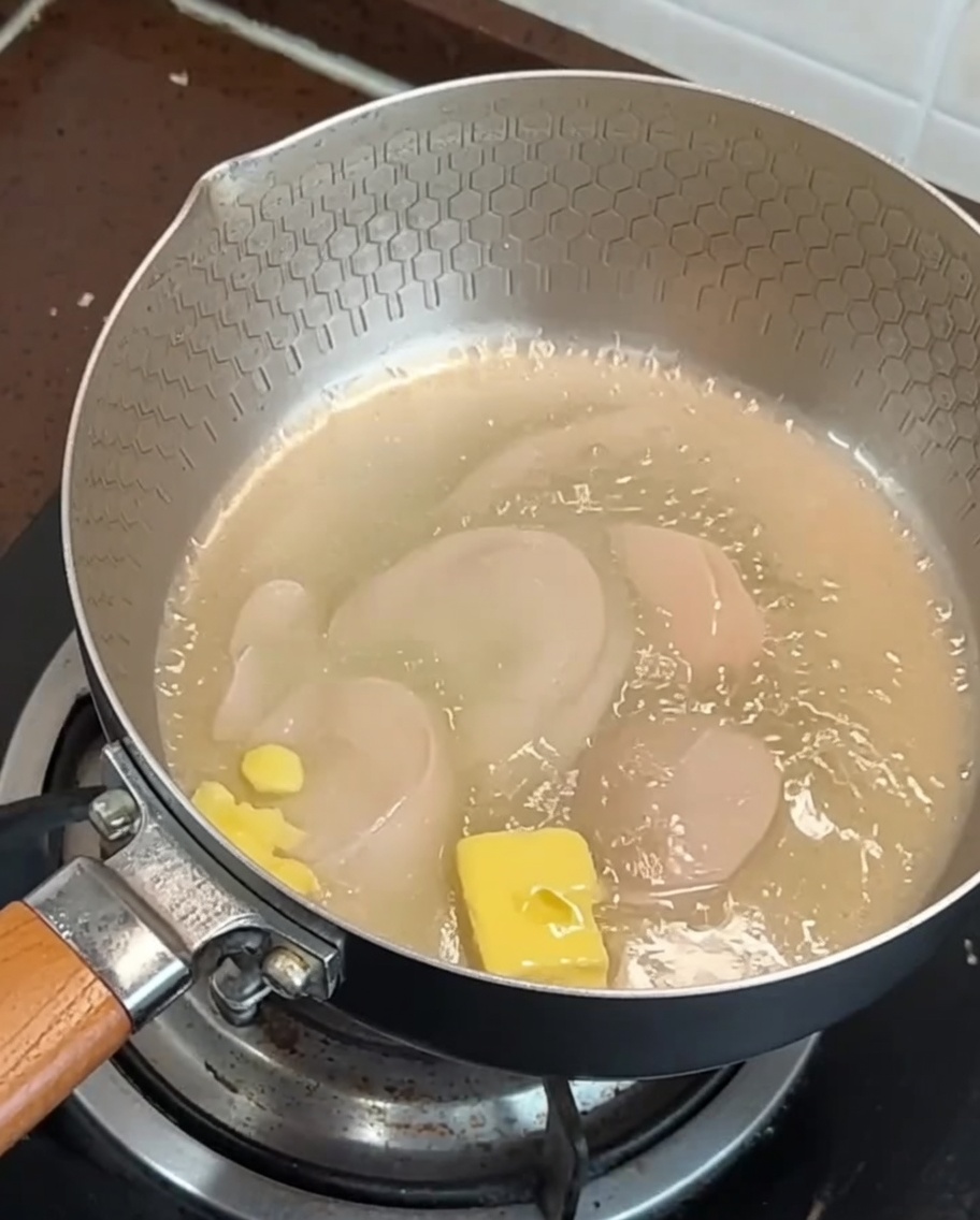 팬 위에서 버터에 녹으며 볶아지고 있는 베이컨 조각과 편마늘.