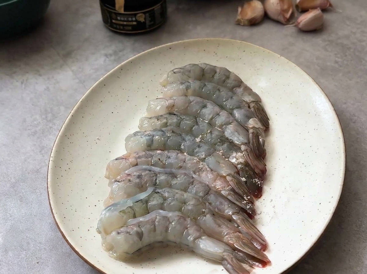 소금과 흑후추로 가볍게 양념한 생새우가 접시 위에 놓여 있는 모습.