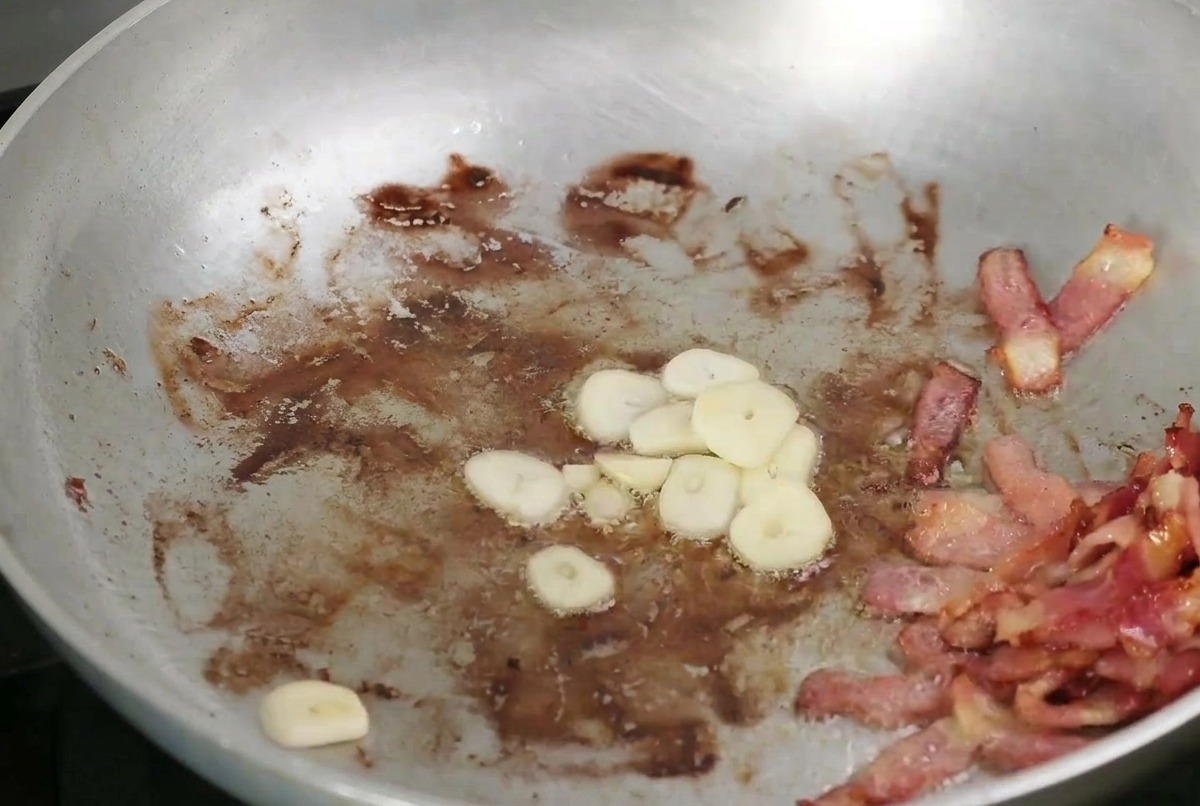 바삭한 베이컨과 함께 볶아지고 있는 얇게 썬 마늘과 버섯.