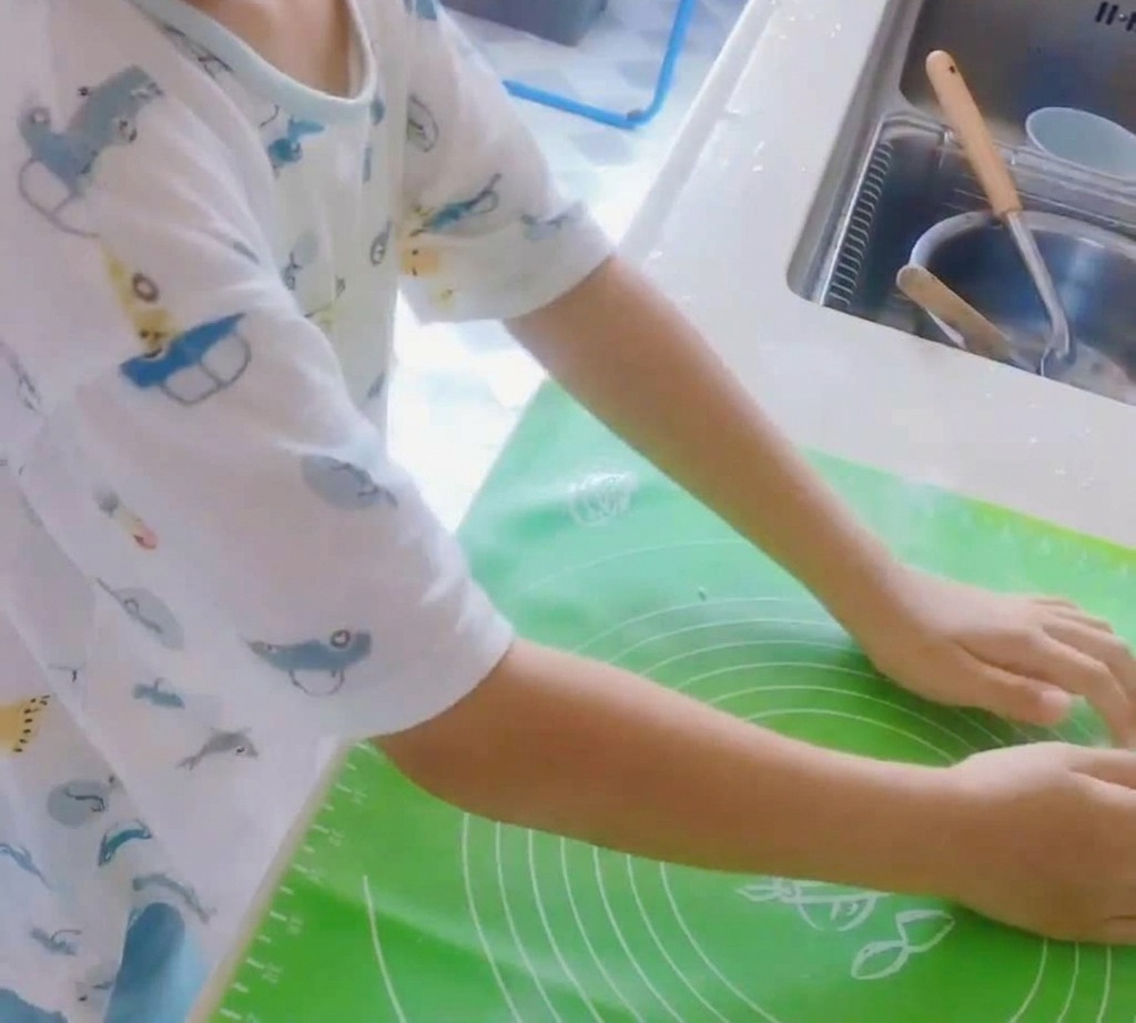 초록색 실리콘 매트 위에서 반죽을 치대는 모습.