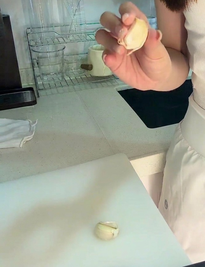 도마 위에서 마늘을 칼로 잘게 다지고 있는 모습.