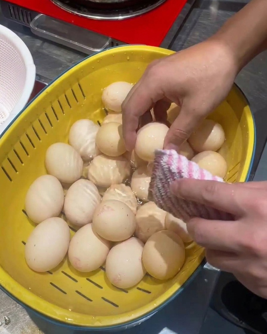 노란 채반에서 수세미로 달걀을 씻는 모습.