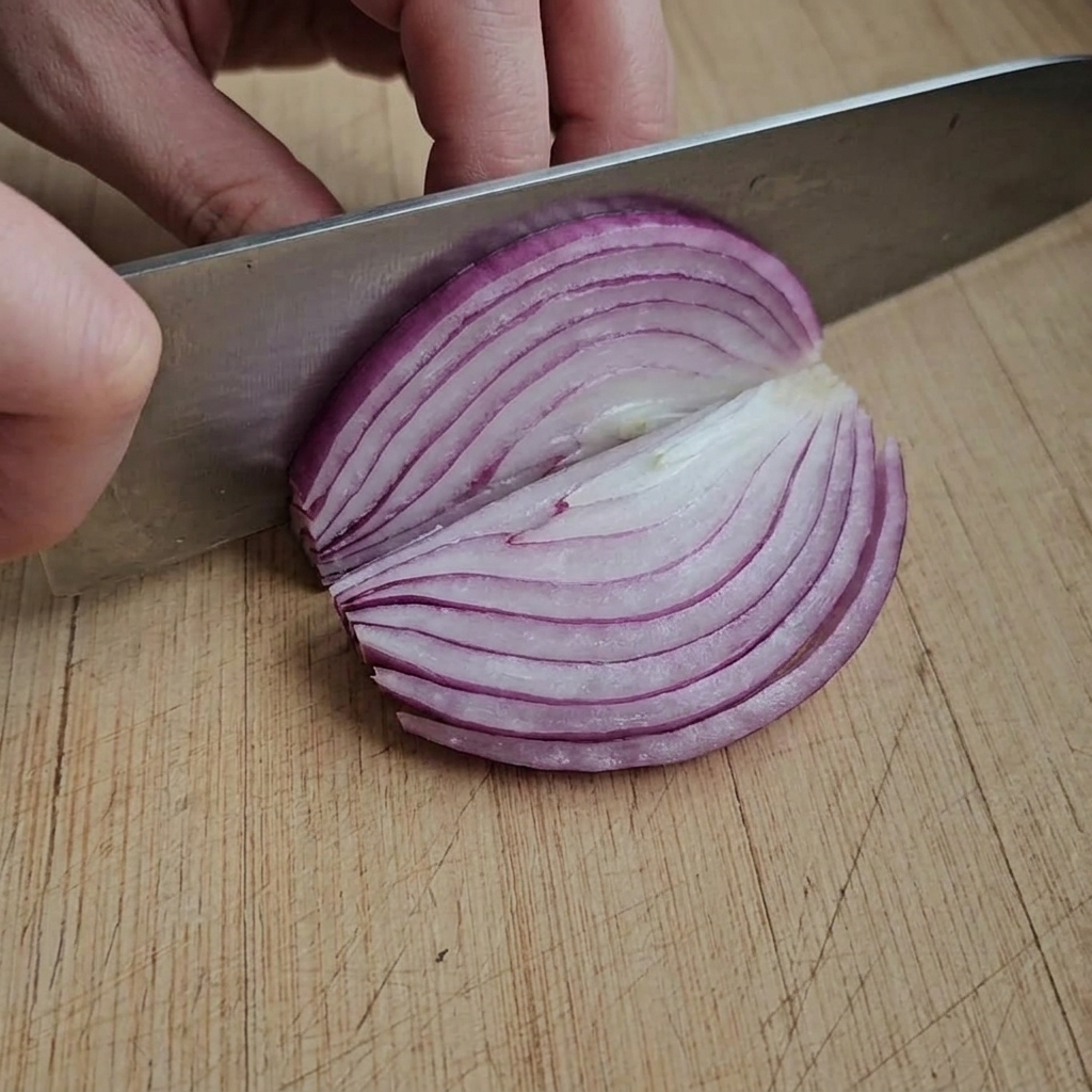 도마 위에 가지런히 놓인 얇게 썬 적양파 조각들.