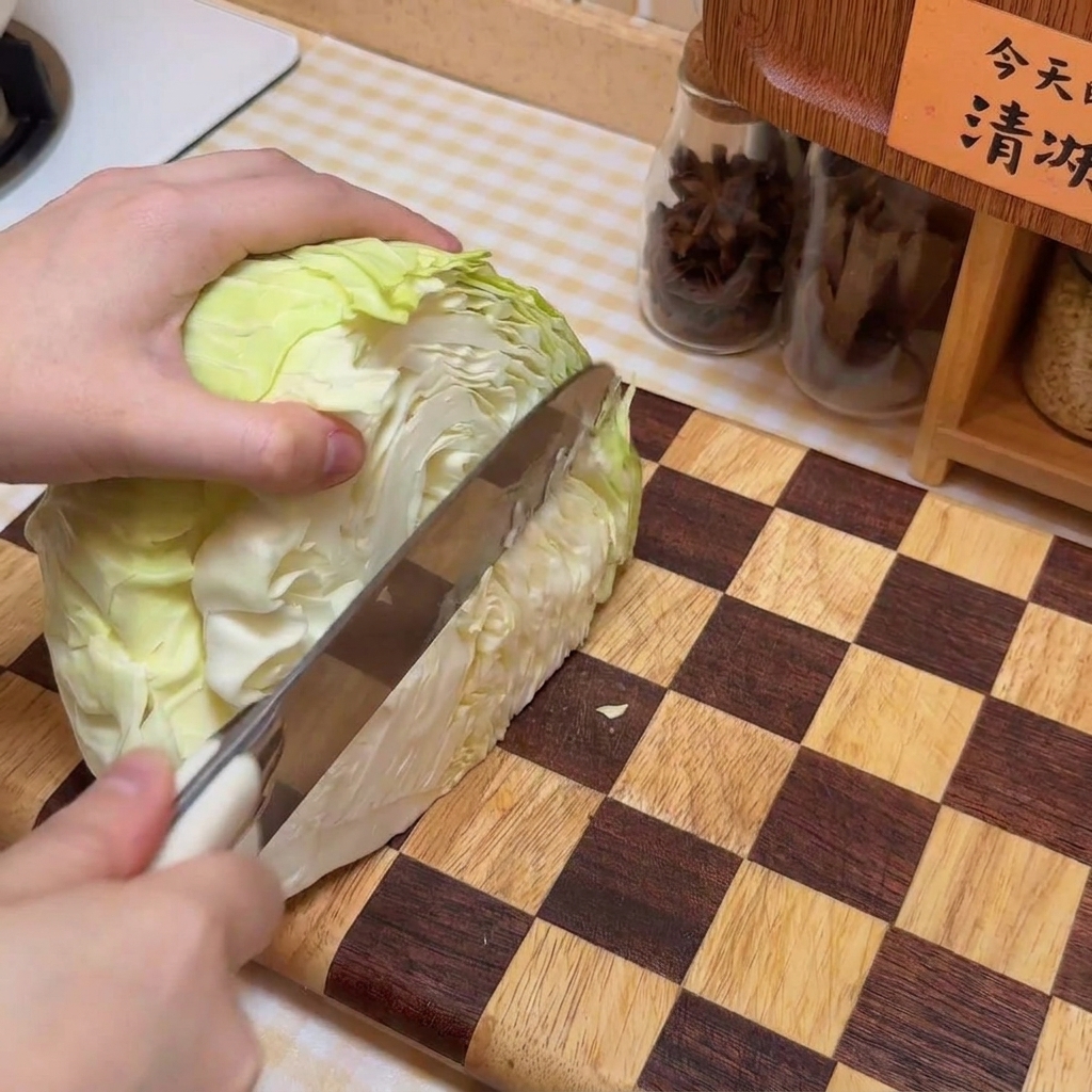 도마 위에서 양배추를 적당한 크기로 썰고 있음.