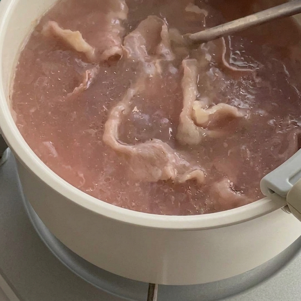 채망으로 끓는 물에서 고기를 건져내는 모습.