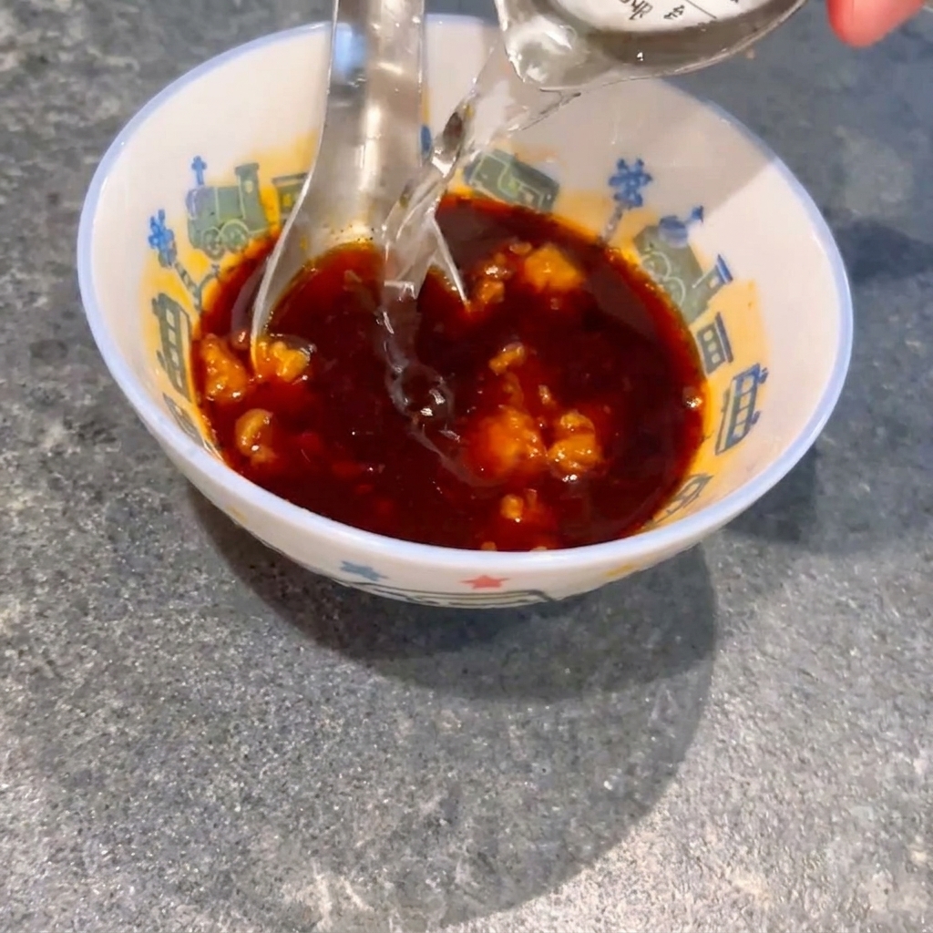 간장과 미소 된장이 담긴 볼에 물을 붓고 숟가락으로 젓는 모습.