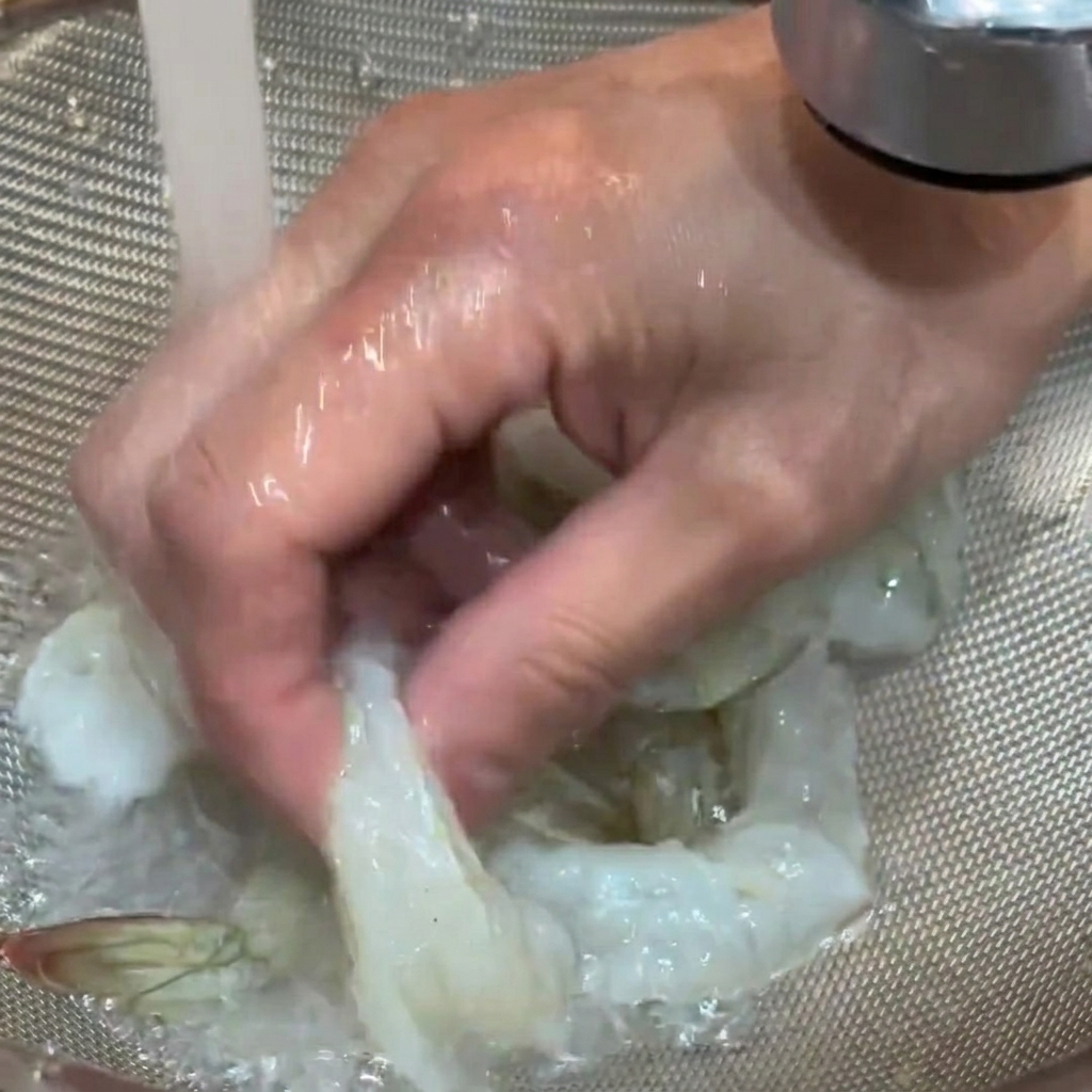 체에 밭친 생새우를 흐르는 수돗물에 헹구는 모습.