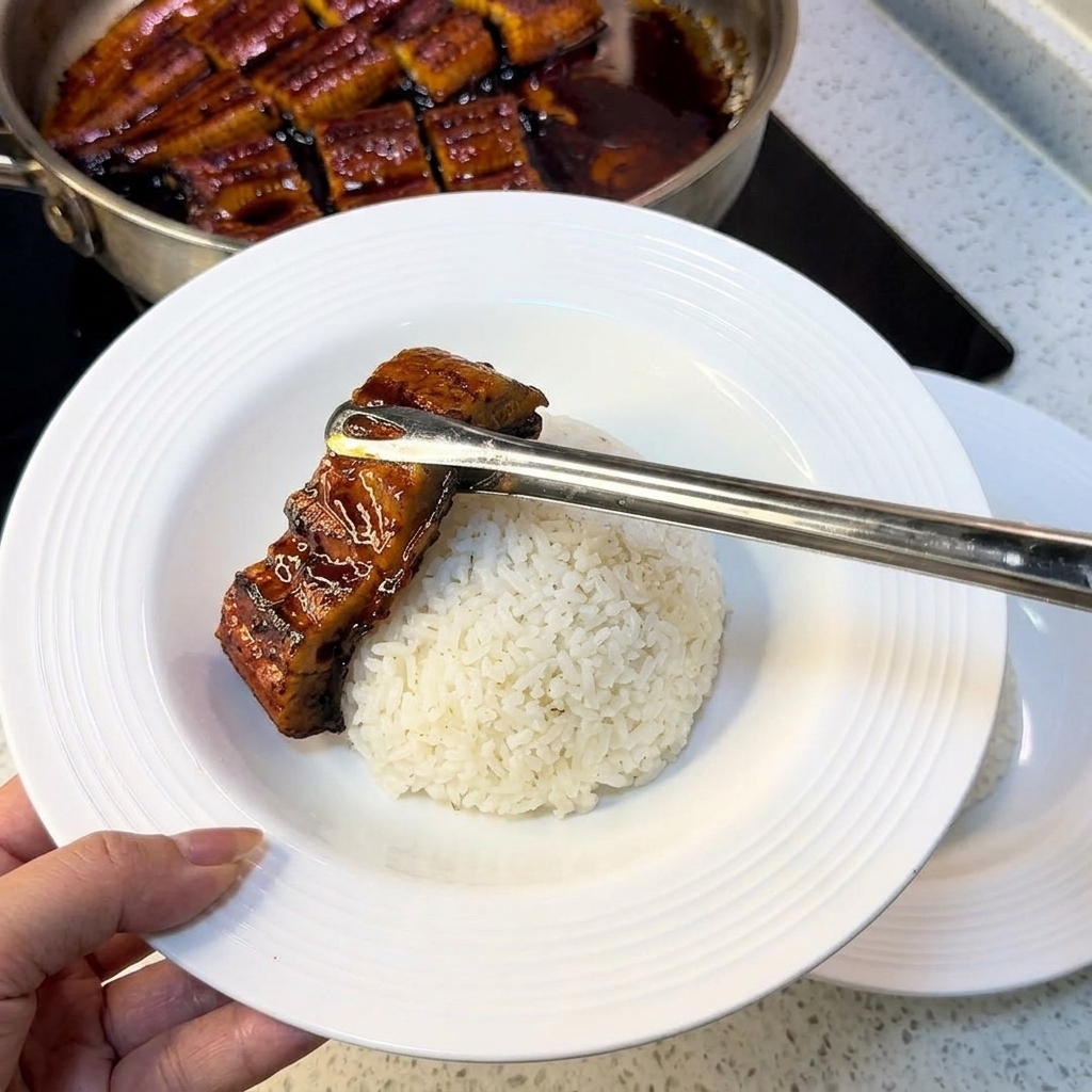 흰 쌀밥 위에 끓인 장어와 달걀지단을 정갈하게 올리는 모습.