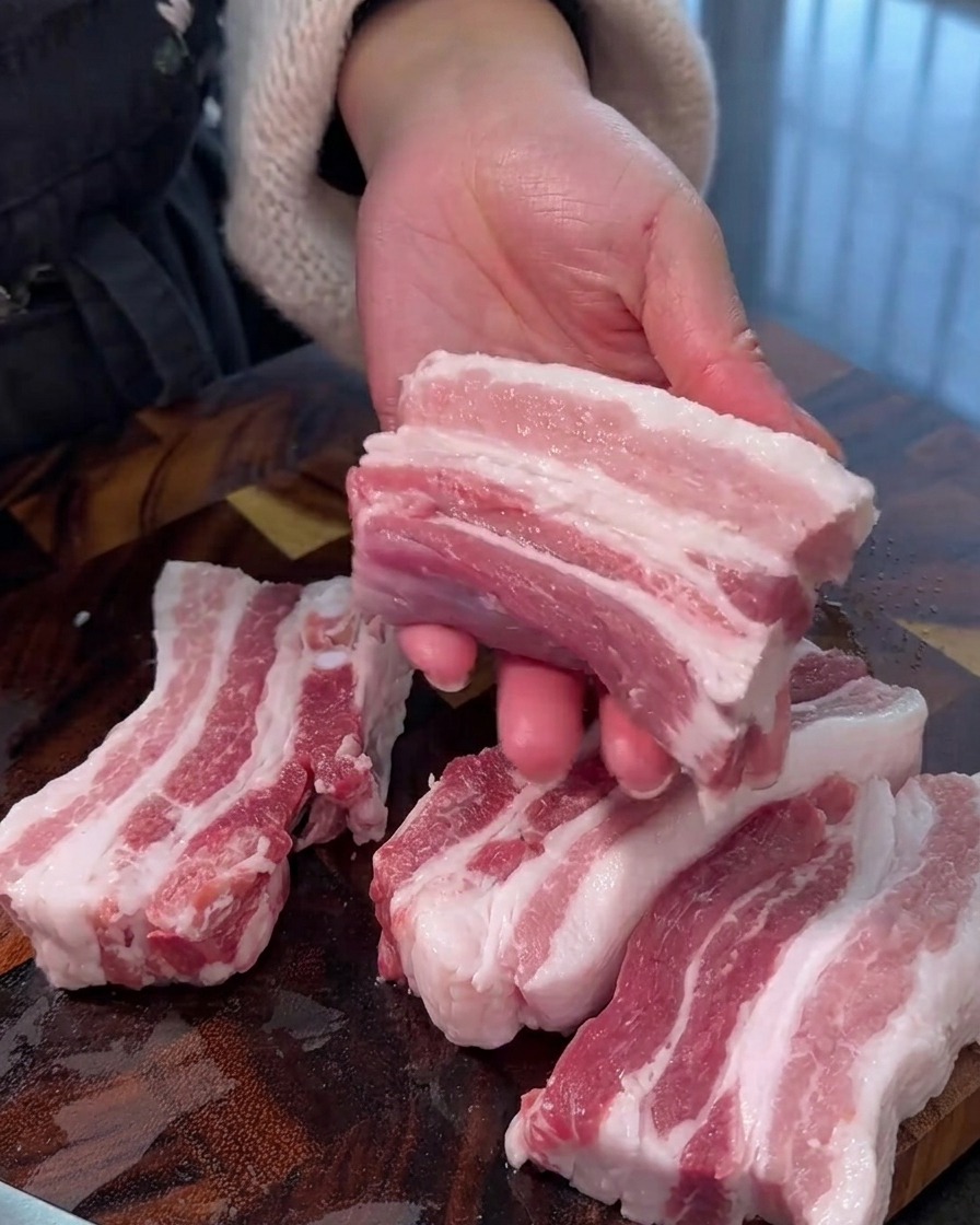 도마 위에서 신선한 삼겹살을 두툼하고 일정한 크기의 스트립으로 썰고 있는 모습.