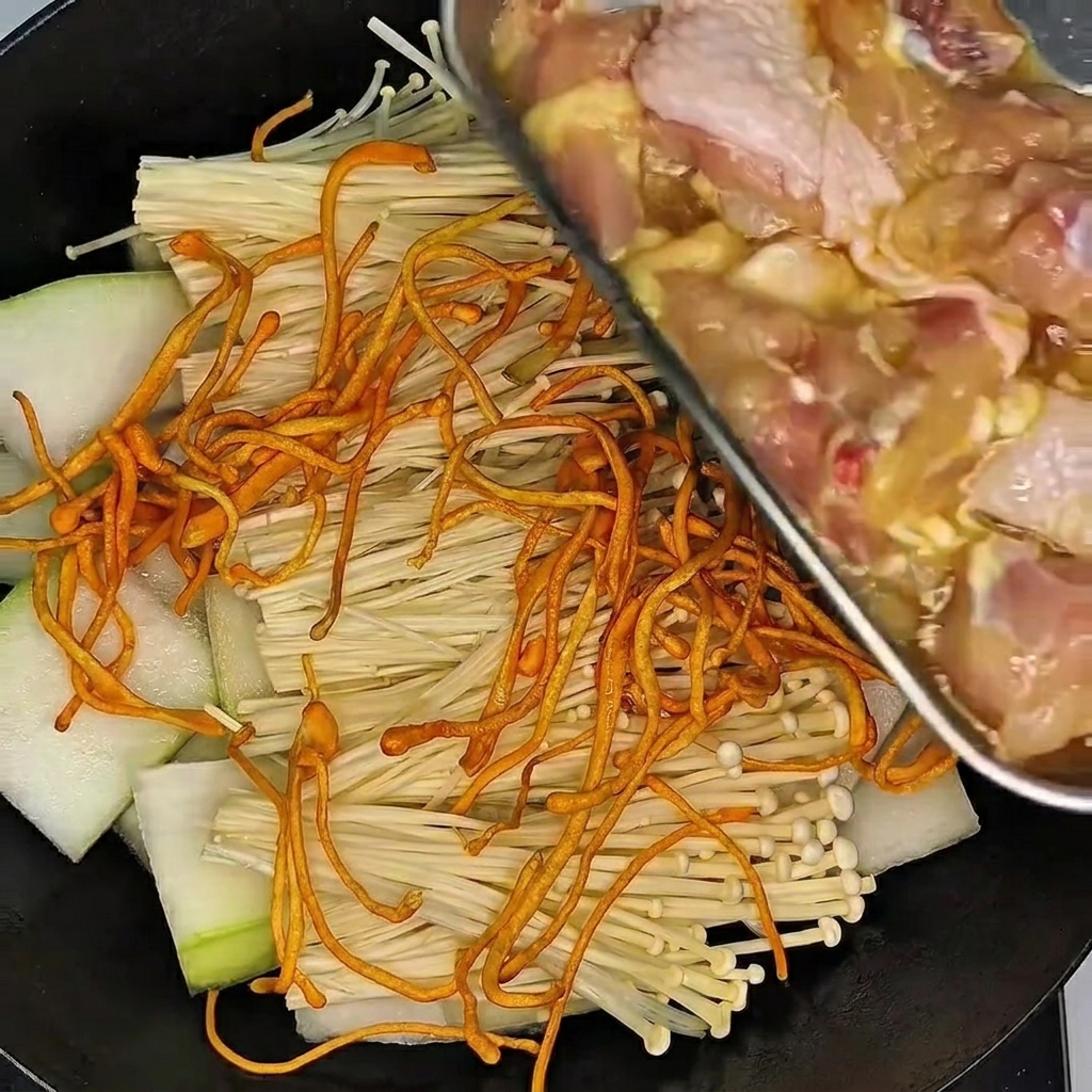 장갑을 낀 손으로 볼 안의 닭다리를 양념과 함께 버무리는 모습.