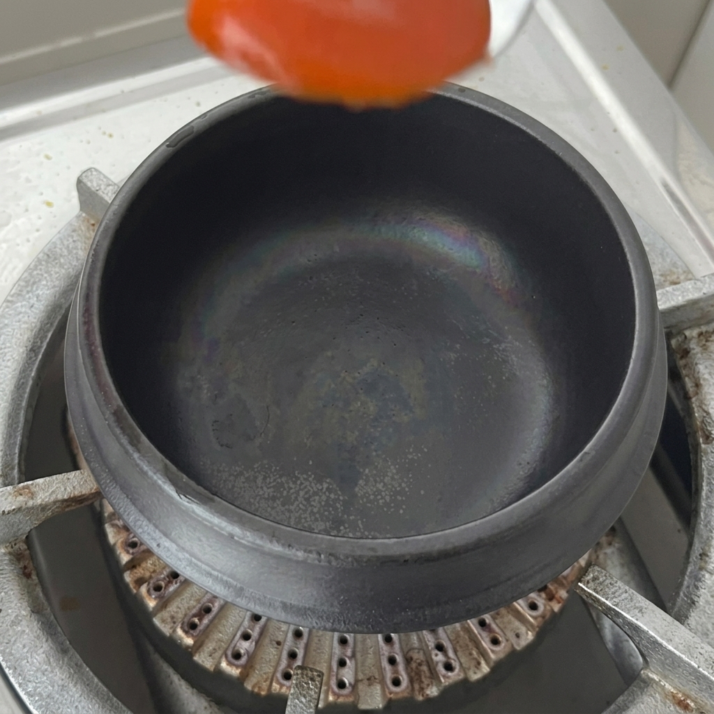 뚝배기 바닥에 고추장 한 숟가락을 올리는 모습.