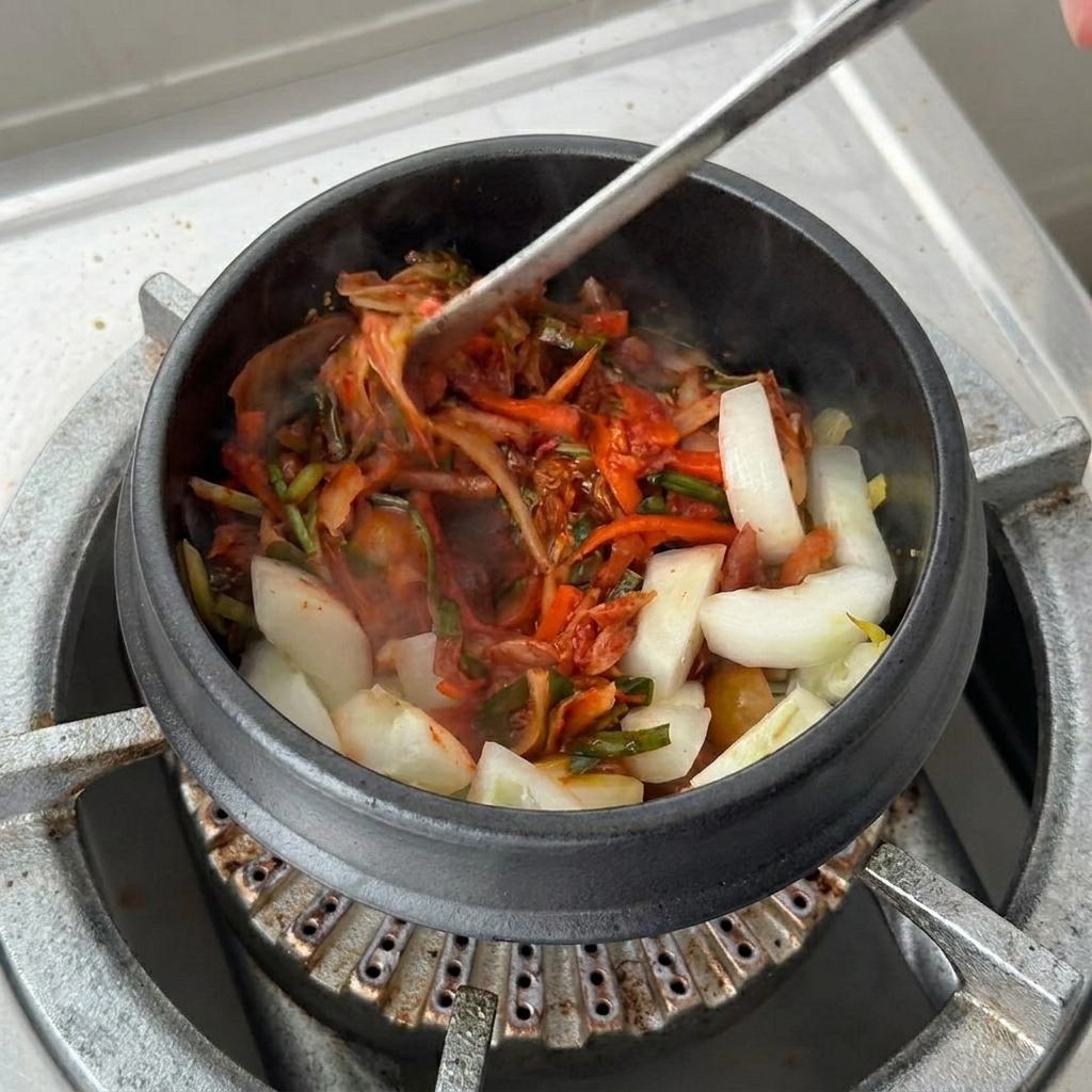 김치 국물을 뚝배기에 붓는 모습.