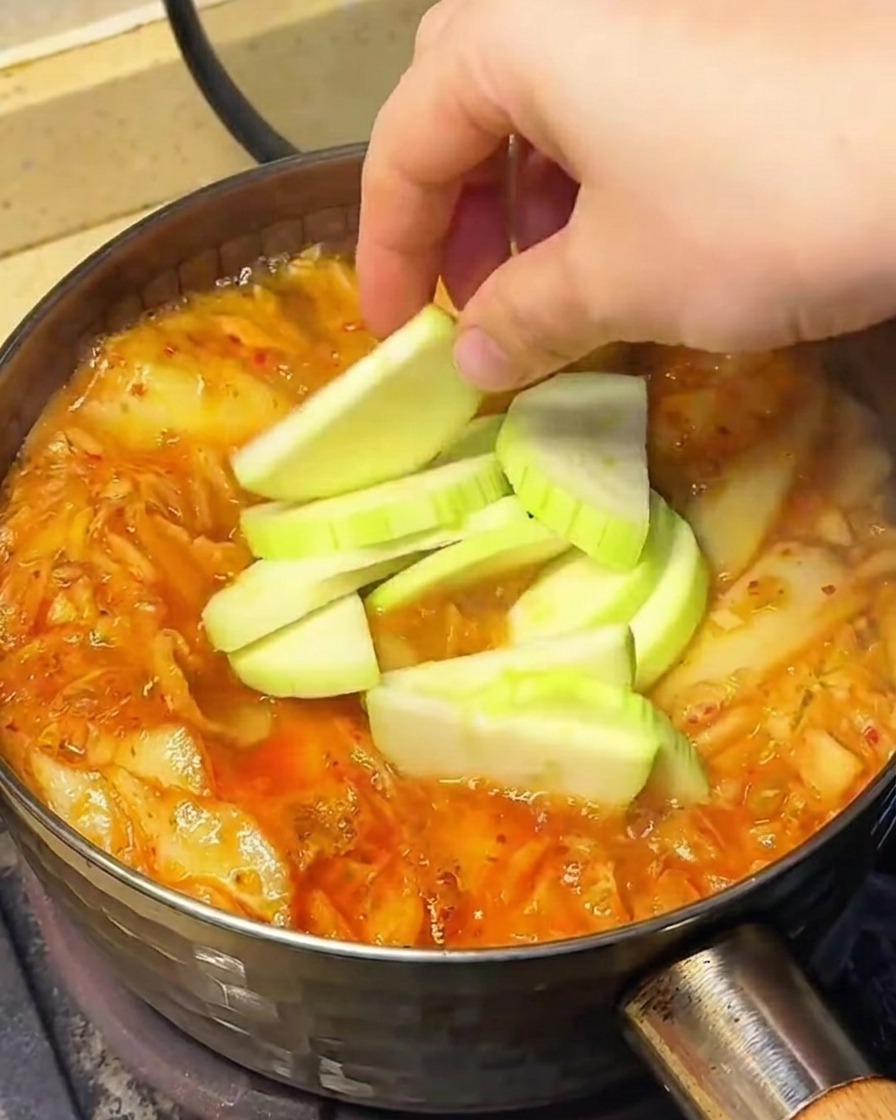 끓는 찌개에 차요테, 숙주, 팽이버섯을 넣는 모습.