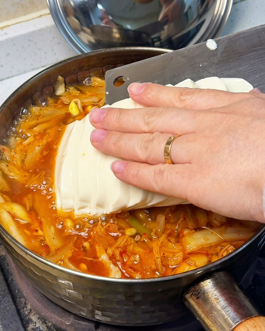 보글거리는 찌개 위에 연두부를 조심스럽게 올리는 모습.