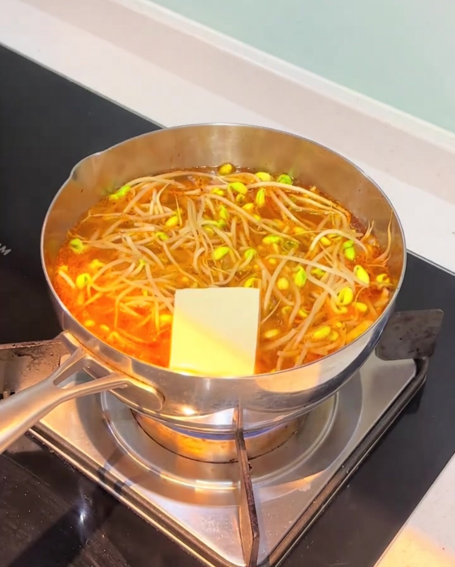 끓는 김치찌개에 두부와 어묵을 넣는 모습.